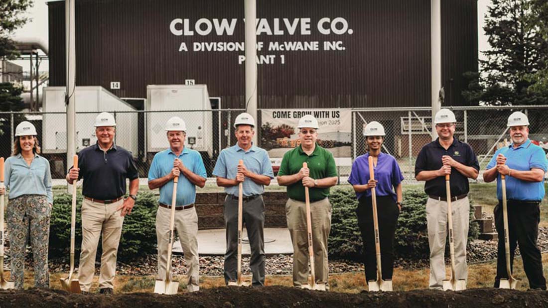 A group of people standing on freshly dug dirt with shovels and smiling.